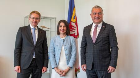 Ministerpräsident Daniel Günther, die Generalkonsulin der Türkei in Hamburg, Emine Derya Kara und der Botschafter der Republik Türkei, Ahmet Başar Şen, stehen nebeneinander im Amtszimmer des Ministerpräsidenten.