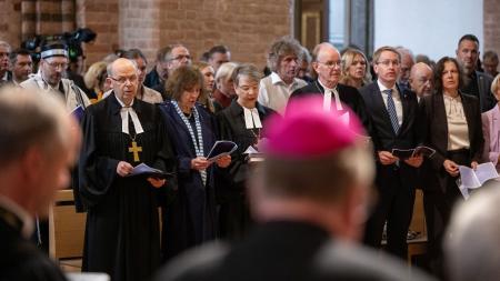 Ministerpräsident Günther steht mit zahlreichen anderen Menschen in einer Kirche und singt ein Lied.