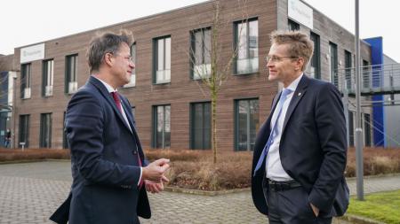 Ministerpräsident Daniel Günther und ISIT-Chef Prof. Dr. Axel Müller-Groeling stehen vor dem neuen Batterie-Forschungszentrum in Itzehoe, einem mit Holz verkleideten Gebäude.