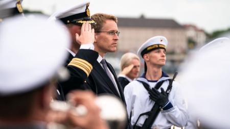 Ministerpräsident Daniel Günther steht zwischen Marinesoldaten auf der Fregatte Schleswig-Holstein.