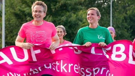 Daniel Günther trägt während des Laufens ein Transparent, rechts neben ihm läuft eine Frau in einem grünen T-Shirt