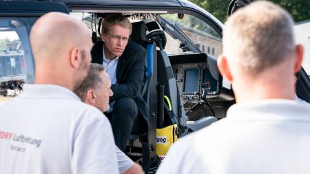 Ministerpräsident Daniel Günther sitzt im Helikopter der Luftrettung und tauscht sich mit der Besatzung aus.