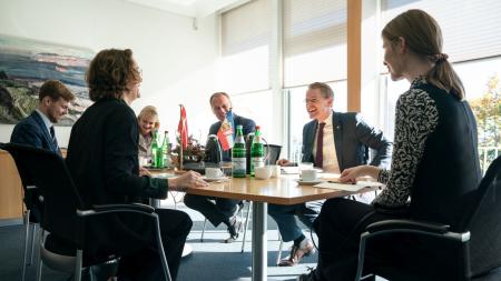 Daniel Günther und der Minderheitenbeauftragte Johannes Callsen sitzen der dänischen Botschafterin Susanne Hyldelund an einem Tisch gegenüber.