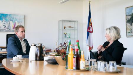 Ministerpräsident Daniel Günther sitzt der Landesbeauftragten für Menschen mit Behinderungen an einem Tisch gegenüber und unterhält sich mit dieser
