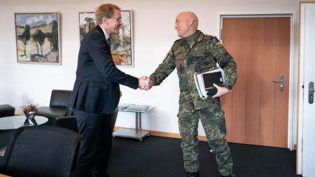 Ministerpräsident Daniel Günther begrüßt den Kommandeur des Landeskommandos Schleswig-Holstein, Oberst Axel Schneider mit einem Handschlag.