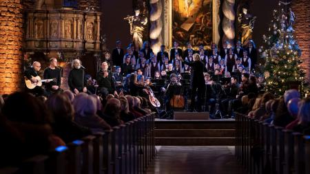 Etwa 50 Musikerinnen und Musiker spielen in einer Kirche ein Konzert.