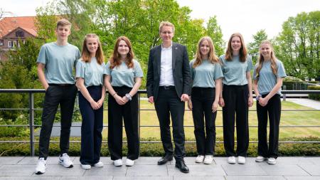 Ministerpräsident Daniel Günther steht mit dem sechsköpfigen Team der schleswig-holsteinischen Schülerfirma 