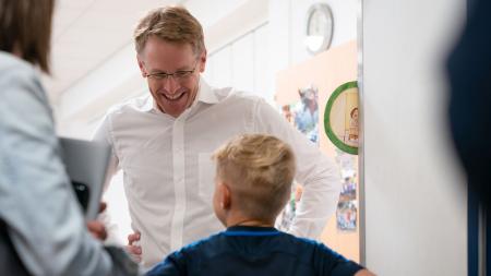 Ministerpräsident Daniel Günther und ein Grundschüler stehen sich gegenüber, der Ministerpräsident lächelt breit.