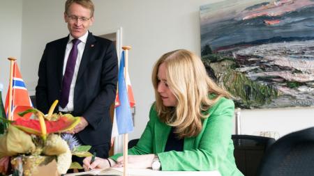 Die norwegische Botschafterin trägt sich in das Gästebuch der Landesregierung ein. Ministerpräsident Günther schaut ihr dabei über die Schulter. 