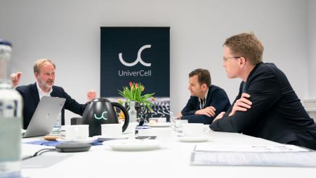 Ministerpräsident Daniel Günther sitzt mit zwei weiteren Männern an einem Tisch.