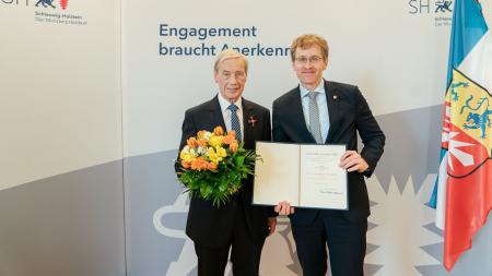 Zwei Männer stehen nebeneinander und halten eine Urkunde