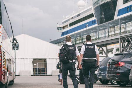 Zwei Polizisten blicken auf ein Kreuzfahrtschiff