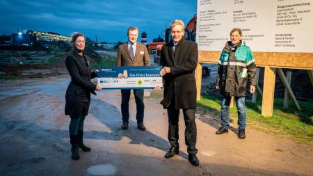 Auf der Baustelle vor dem Multimar Wattforum überreicht Ministerpräsident Günther der Projektleiterin Marén Bökamp-Hamkens den Förderbescheid. Dahinter stehen Michael Kruse (Leiter Nationalparkverwaltung) und Gerd Meurs-Scher (Leiter Multimar Wattforum).