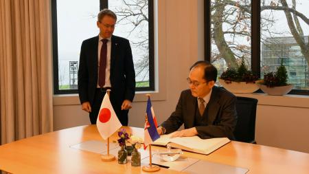Der japanische Botschafter schreibt ins Gästebuch der Landesregierung. Ministerpräsident Günther schaut ihm dabei über die Schulter. 