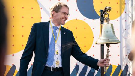 Ministerpräsident Daniel Günther läutet eine Glocke.
