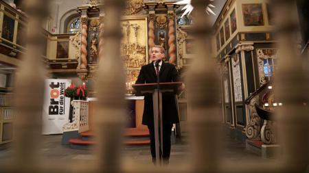 Ministerpräsident Daniel Günther steht in einer Kirche und spricht.